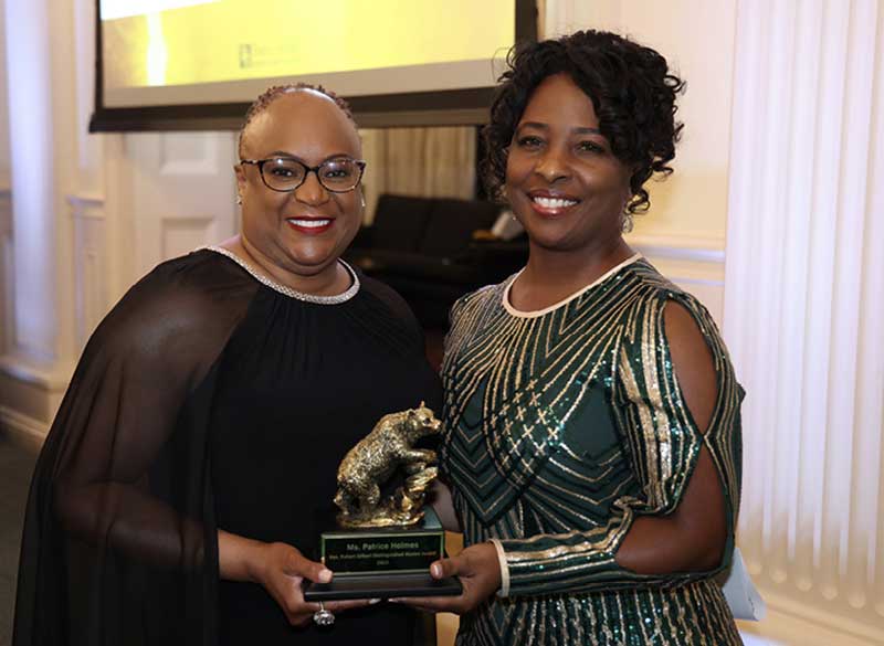 Sandra Silmon, B.A. ‘95 (R) presents the Distinguished Black Alumni Award to Crystal Woods, B.S. ‘97 (L) on behalf of Col. Patrice Holmes, 
B.S. ‘97.
