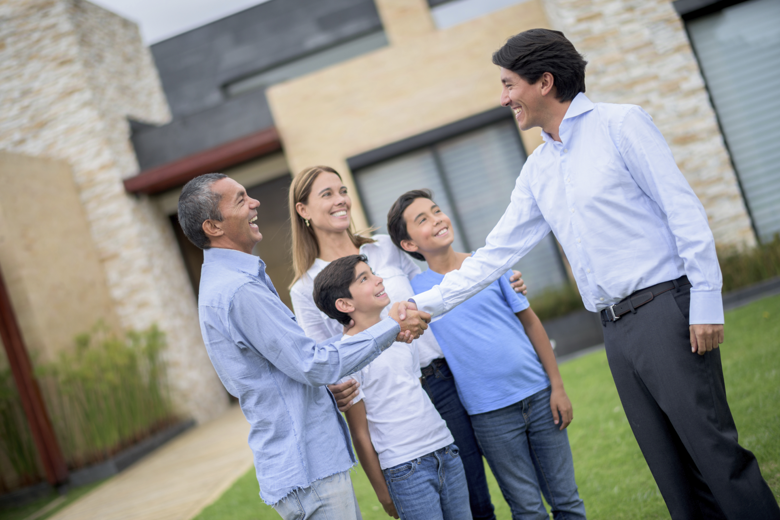 stock photo of realtor closing deal with a family in the front yard