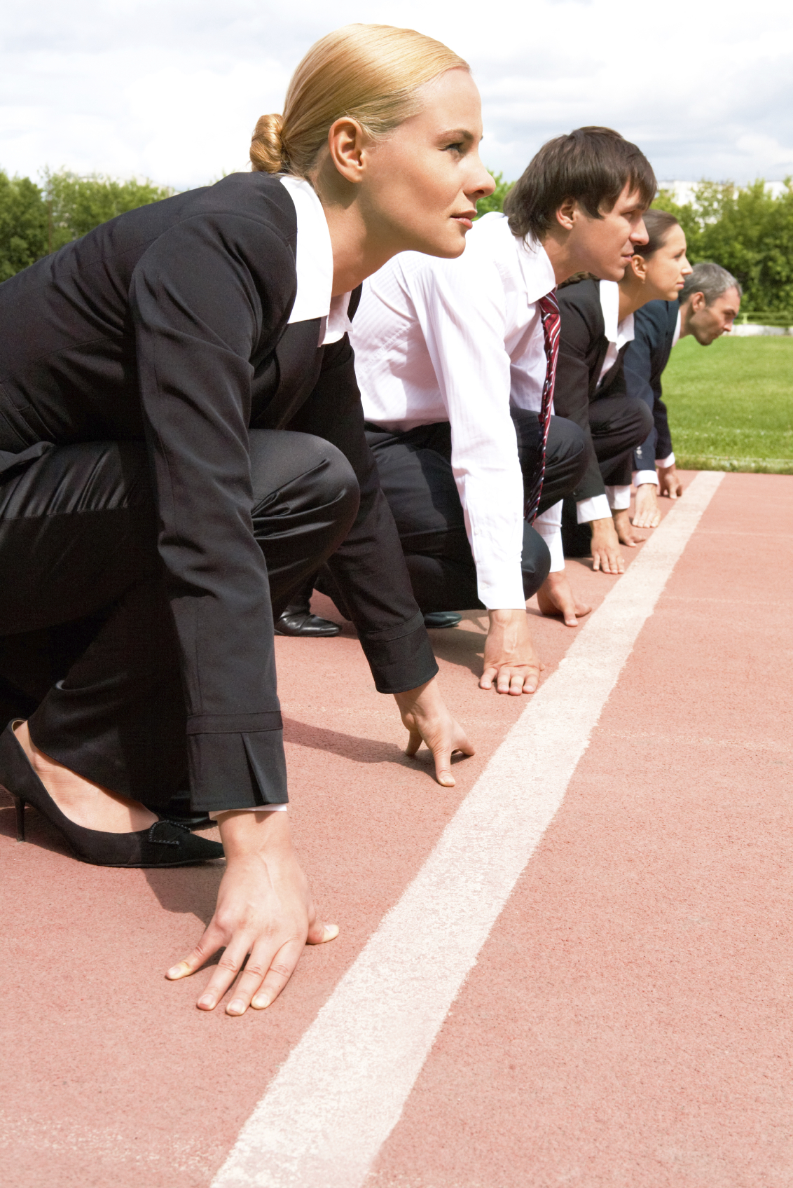 Stock photo of business men and women in business attire at the starting line of a track