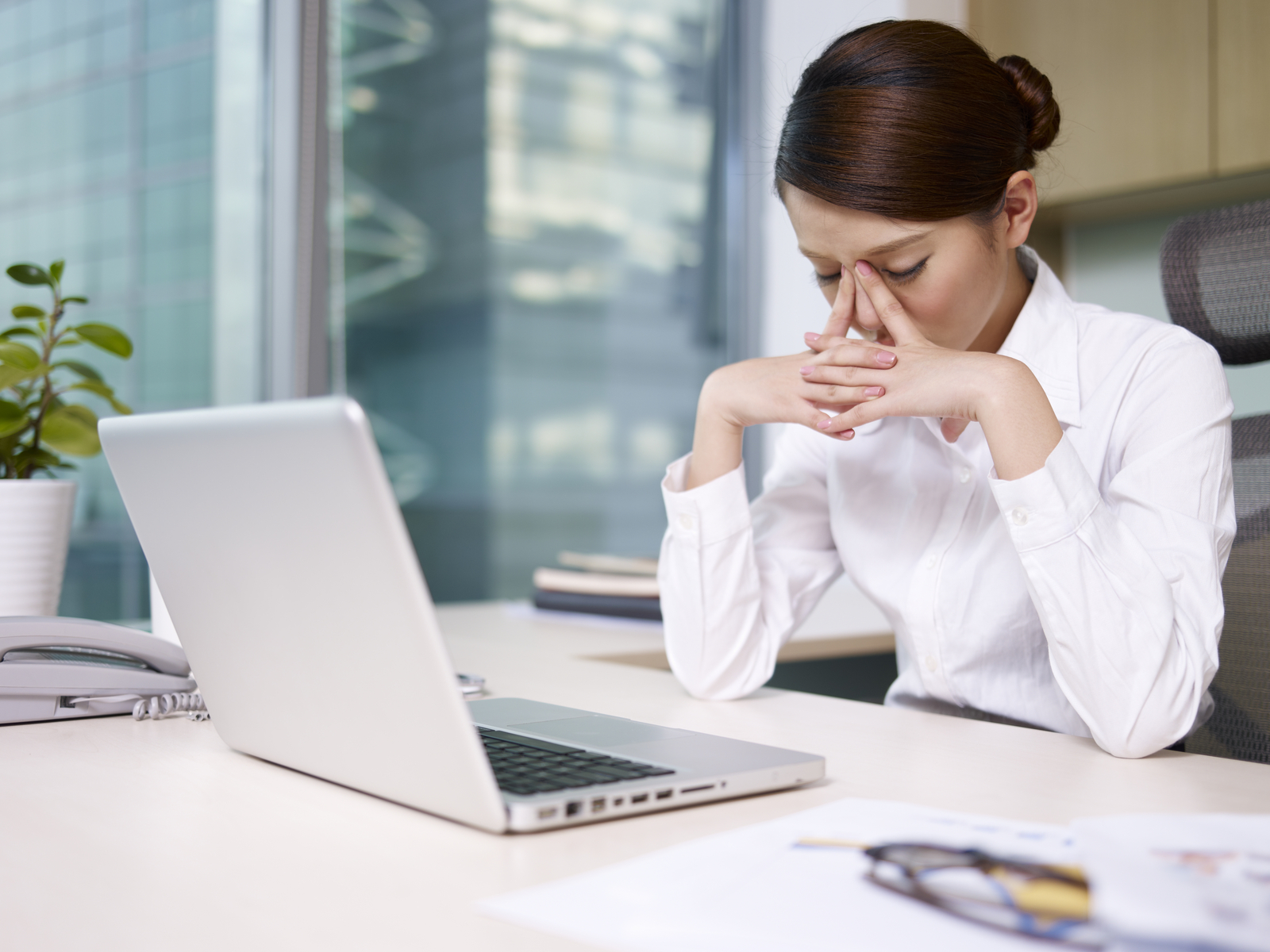 Stock photo of a businesswoman thinking at her desk, disappointedly