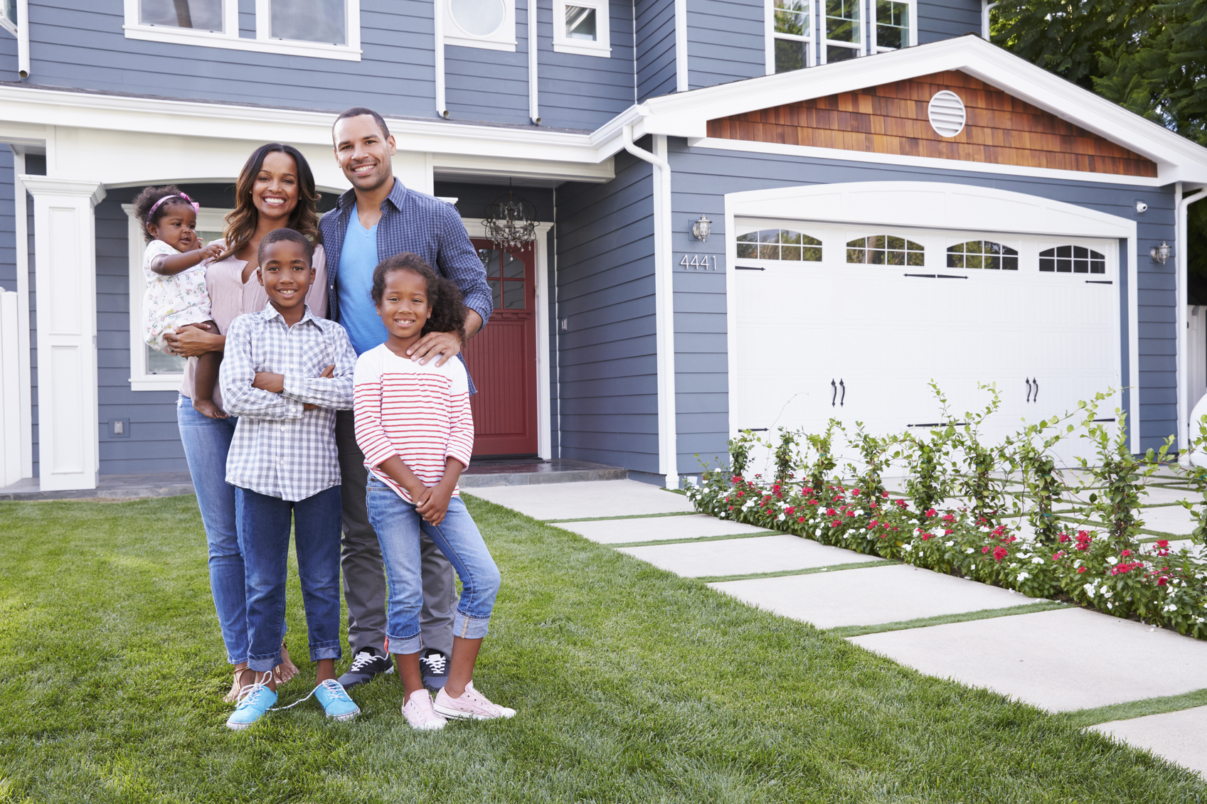 Stock photo of a family standing out front of their home