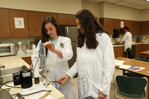 Two Students in Lab Coats Study A Microbiome at a lab bench