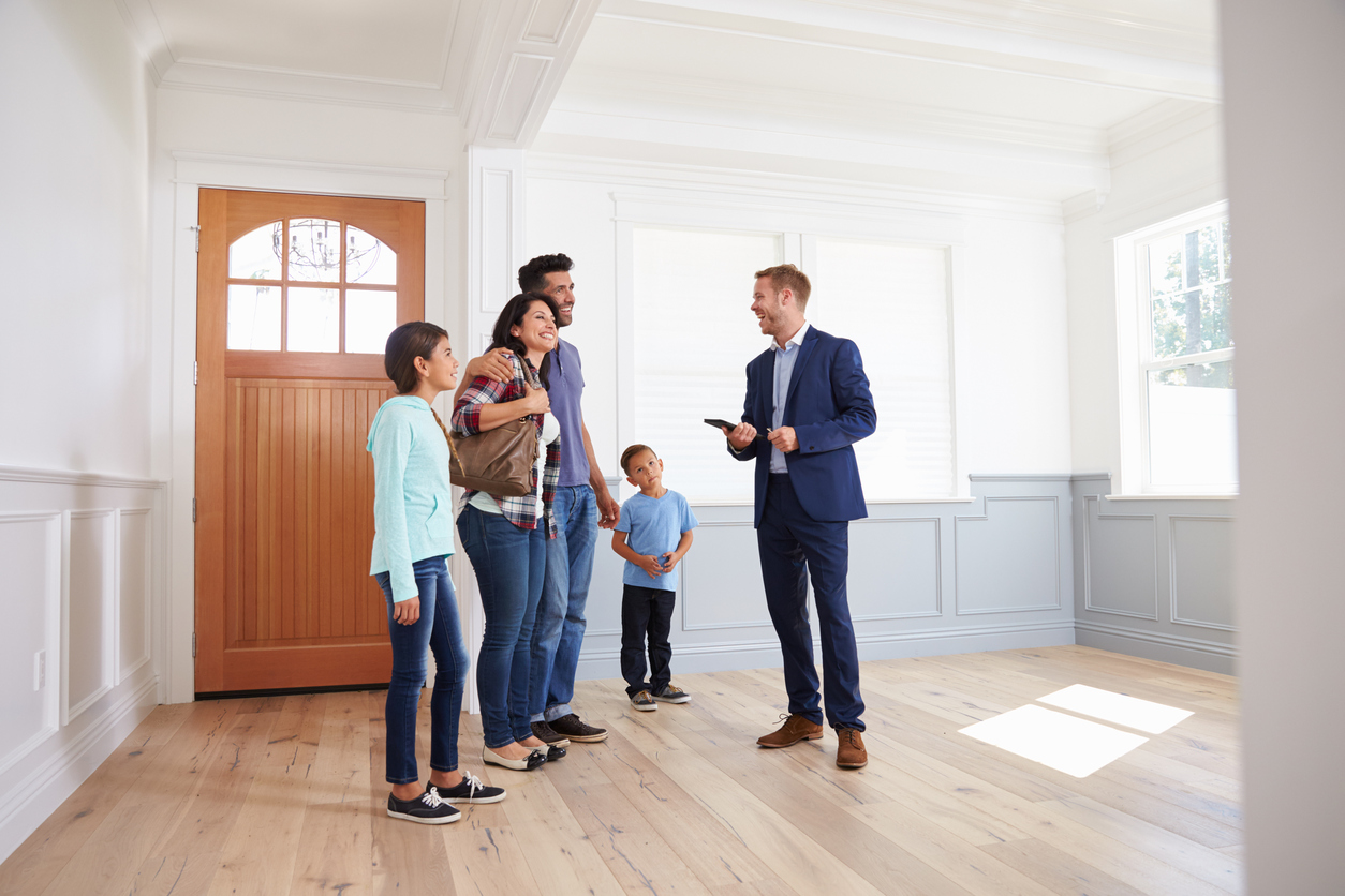 A real estate salesman laughs as he explains to a family