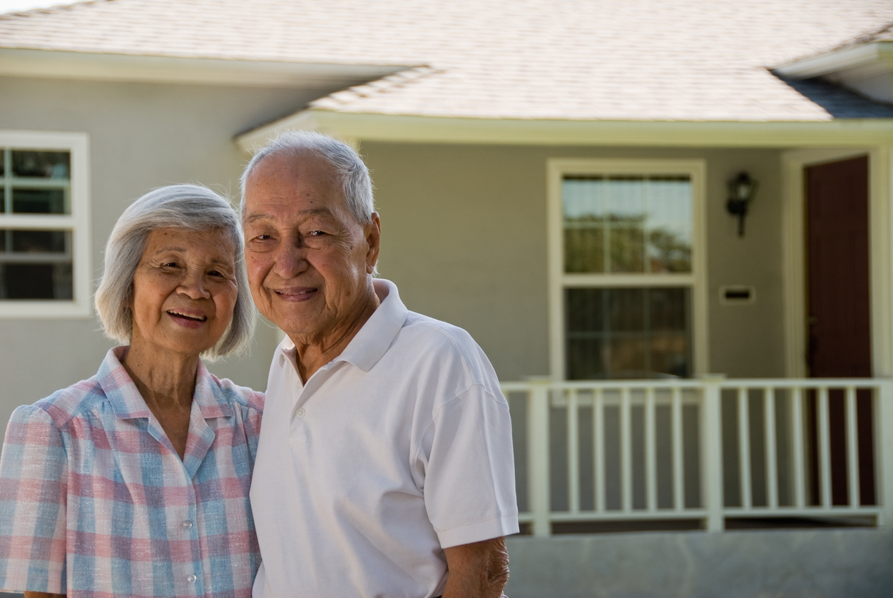 Stock photo of elderly couple in front of a home