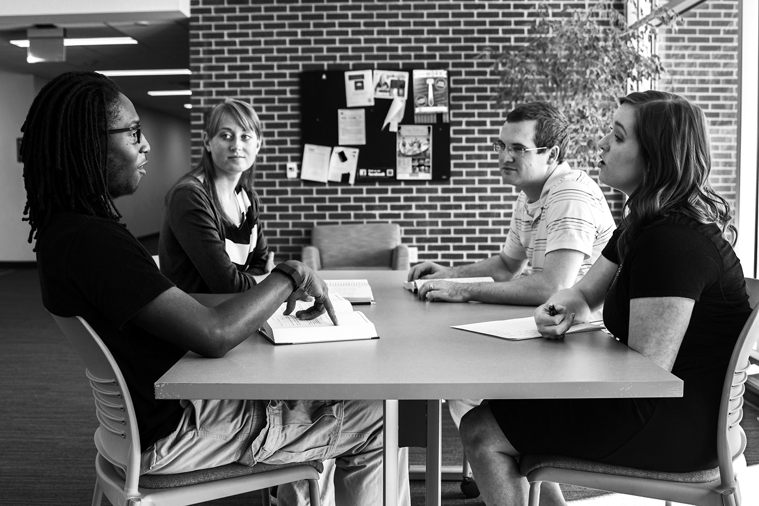 Students and faculty gather around a table to discuss ideas