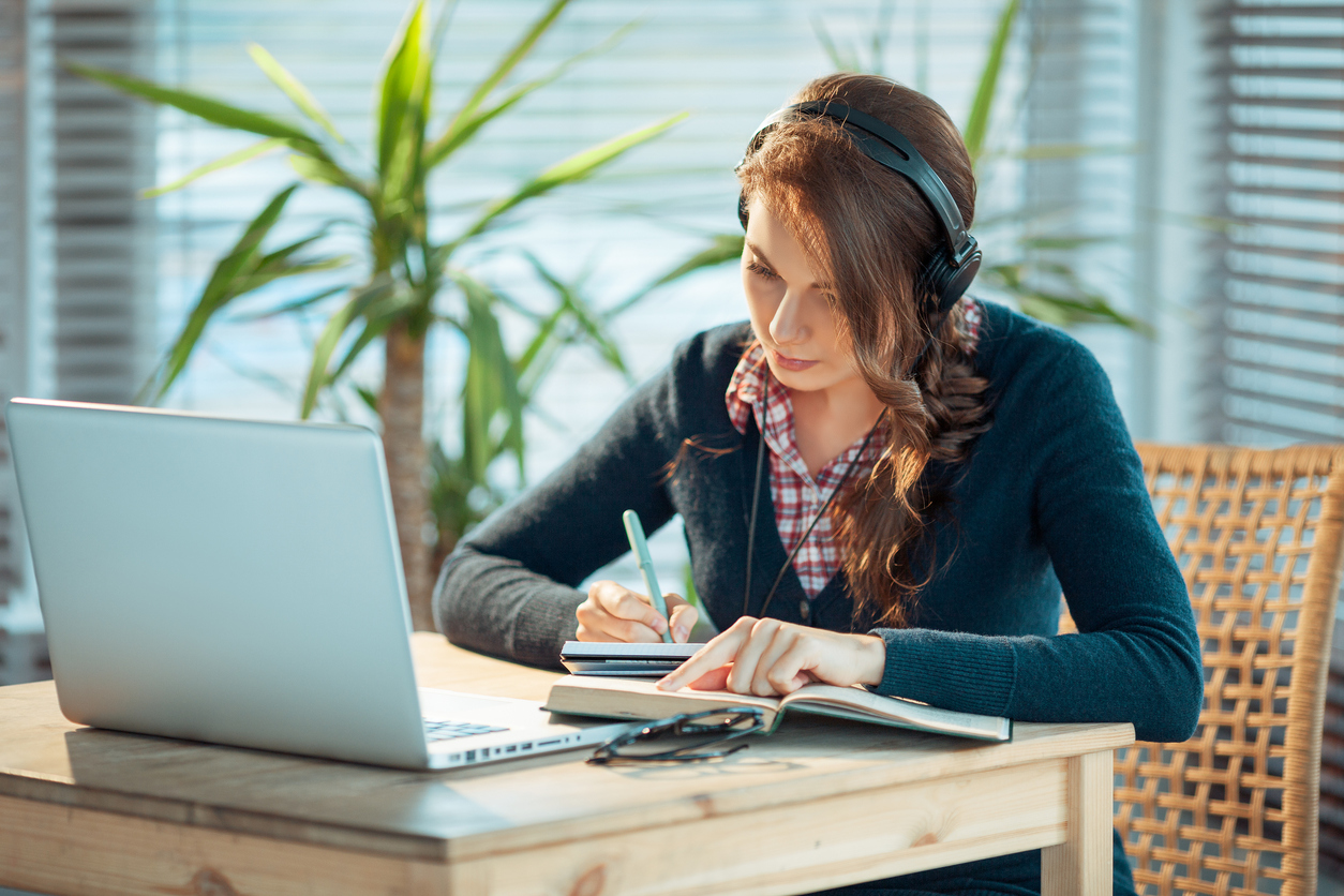 Stock photo of woman wearing headphones studying at a laptop