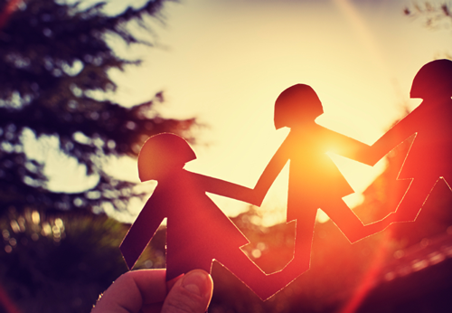 Stock photo of a paper chain of figures against a sunset