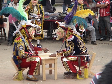 Entertainers clad in colorful garb and masks entertain in a town square