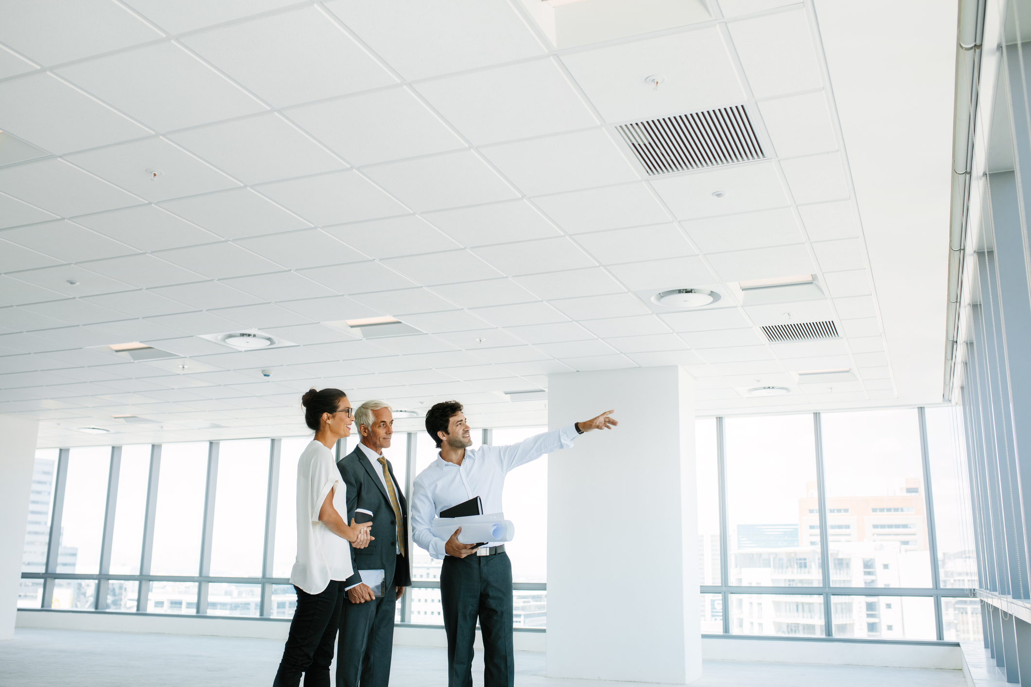 Stock photo of a male showing a couple a vision, pointing out a high-rise building