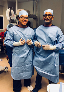 Two pre-medical students stand in full radiology gear and masks