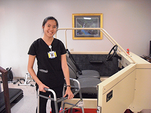 An occupational therapist demonstrates how one uses a walker to get into a car