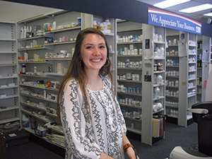 A female student poses in front of a pharmacy