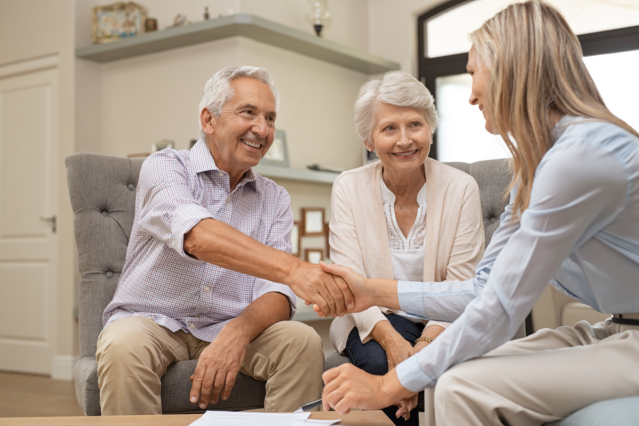 Stock photo of an older couple shaking hands with a young realtor