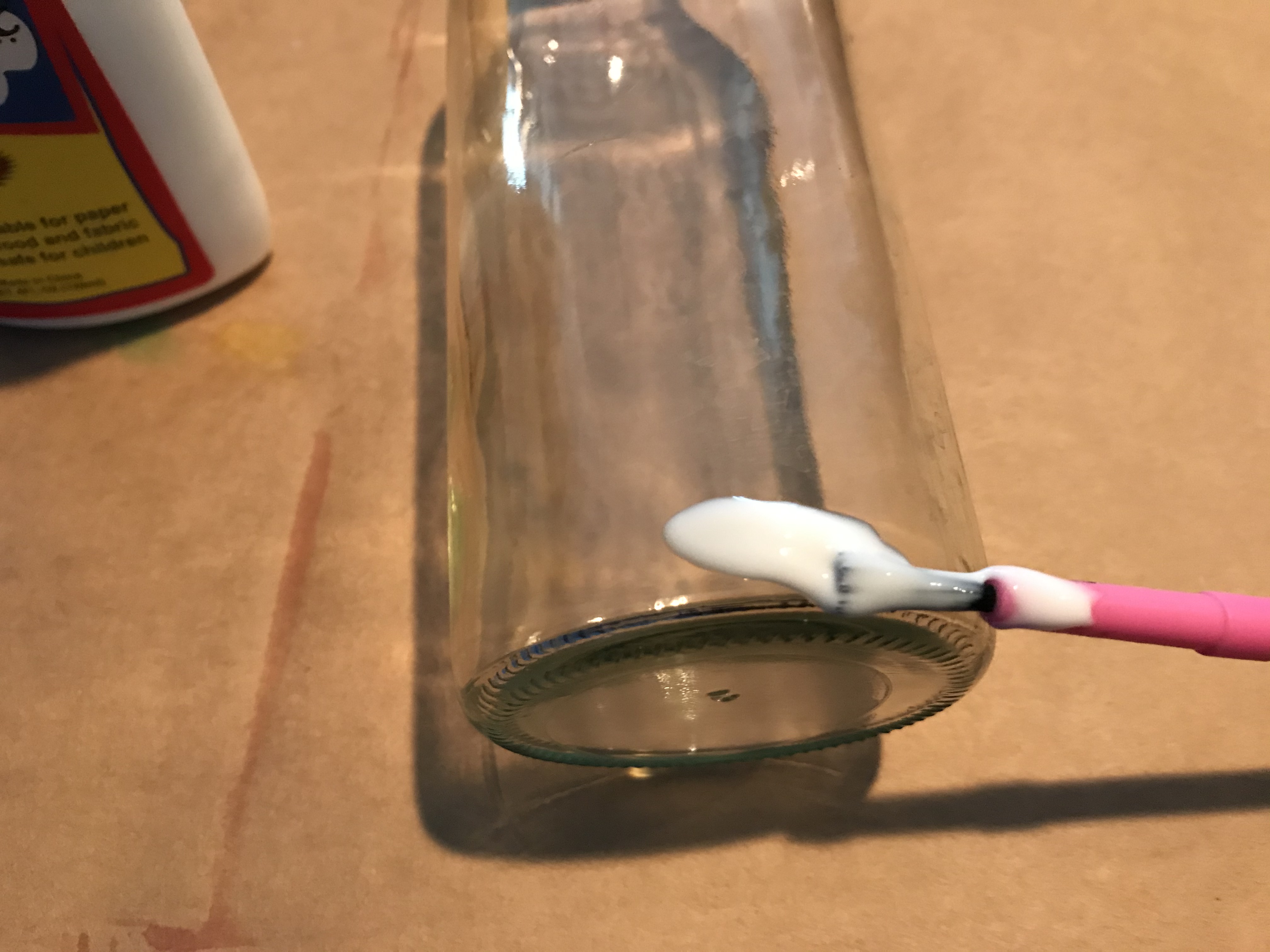 Apply glue with the brush all the way around the lowest portion of the bottle or jar.