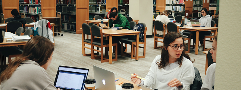 Photo of Moody study commons, with students studying on various tables and even some seated on the floor