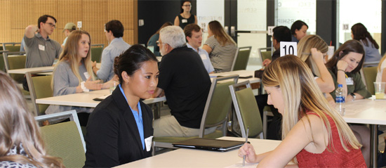 Several students in a room doing one-on-one interviews