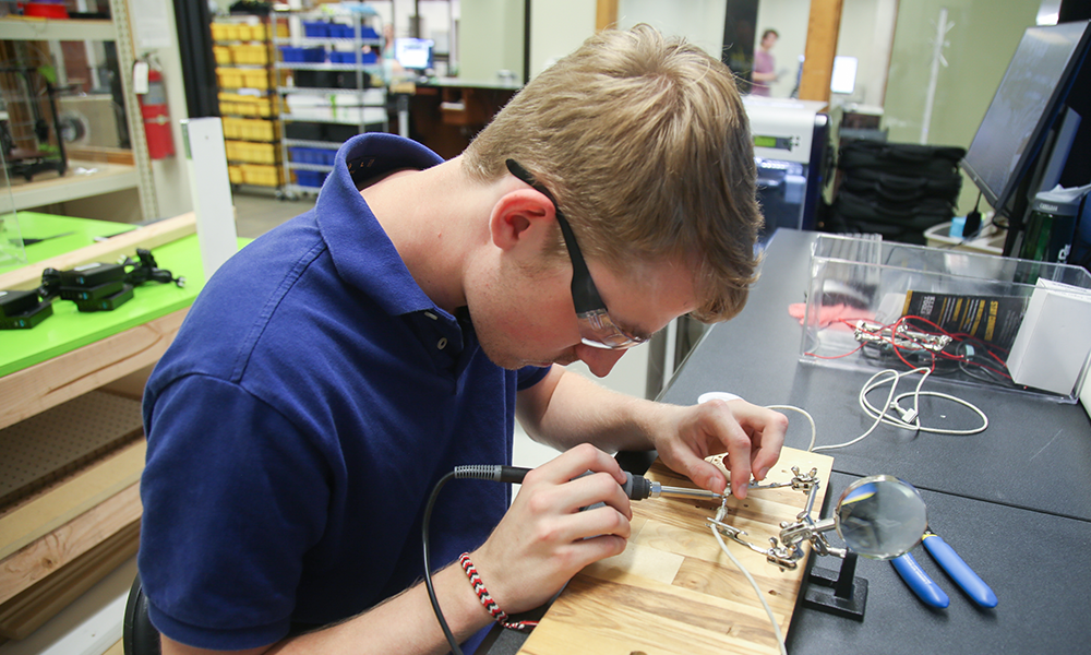 Photo of Student Using tools to create in the Makerspace
