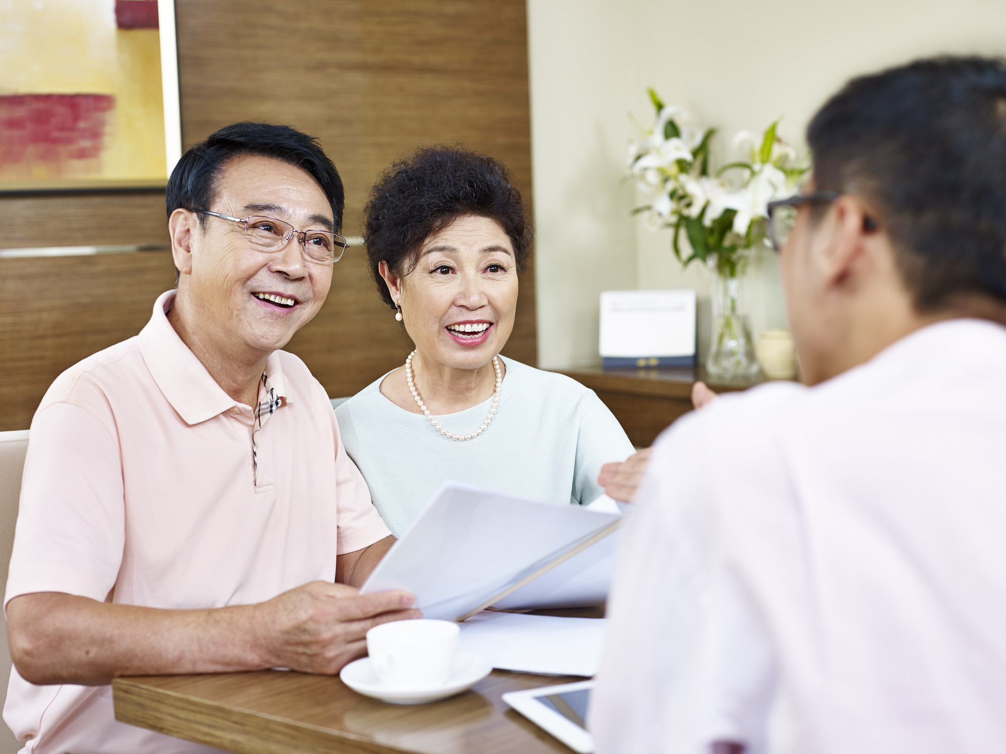 Stock image of senior asian couple meeting with realtor, who is showing them a piece of paper