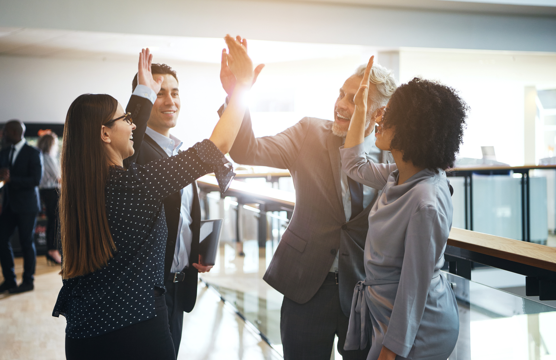 Stock photo of a group of four coworkers high fiving