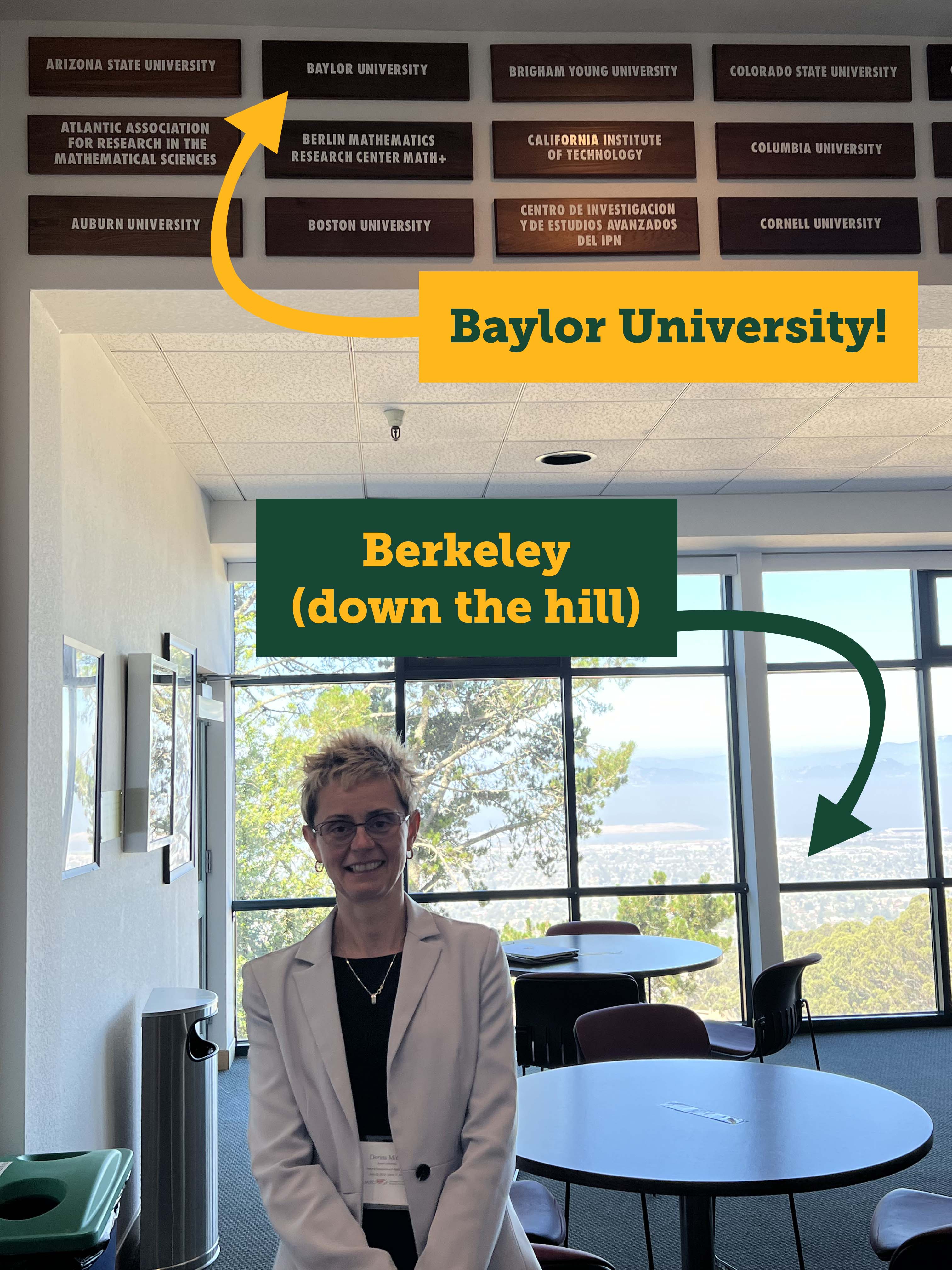 Dr. Dorina Mitrea stands at MSRI below a plaque with Baylor University written on it. Out the window we see a view that looks out over Berkeley and down to the San Francisco Bay.